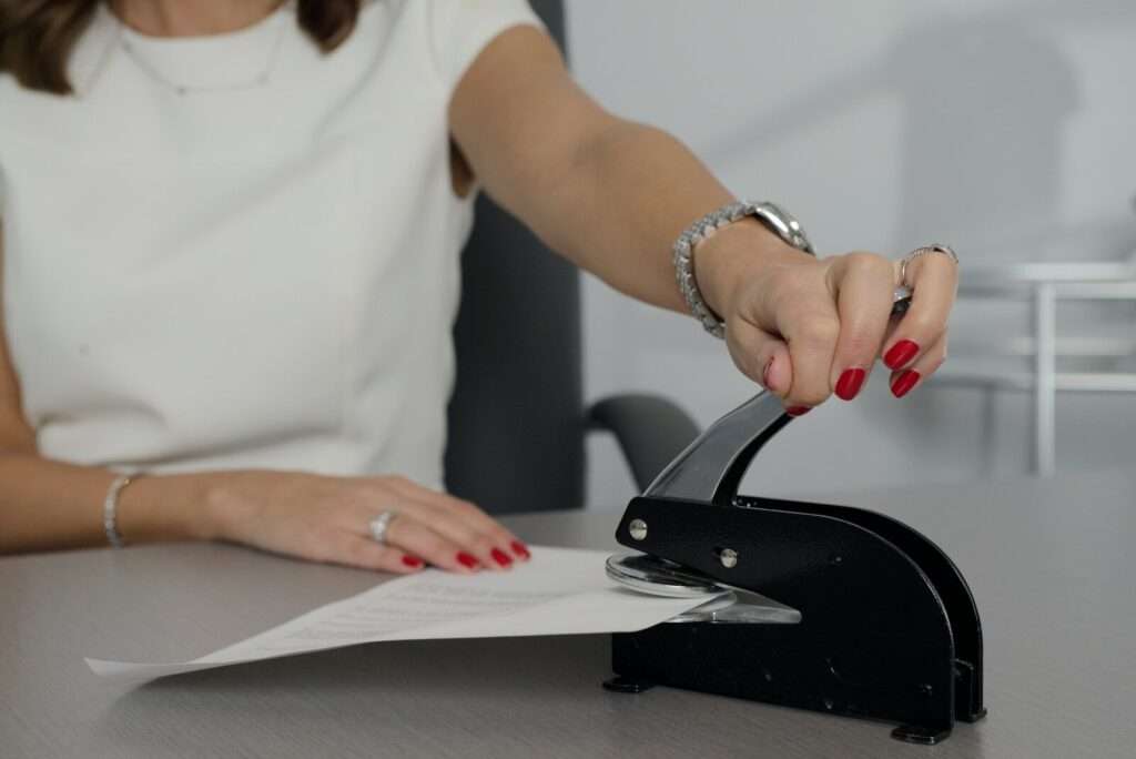 woman in white shirt holding pen writing on white paper notary